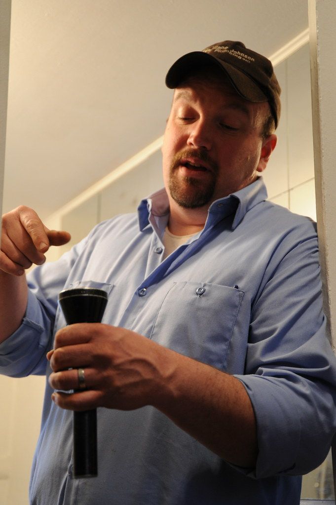 Plumber inspecting a drain with a flashlight in Cerritos